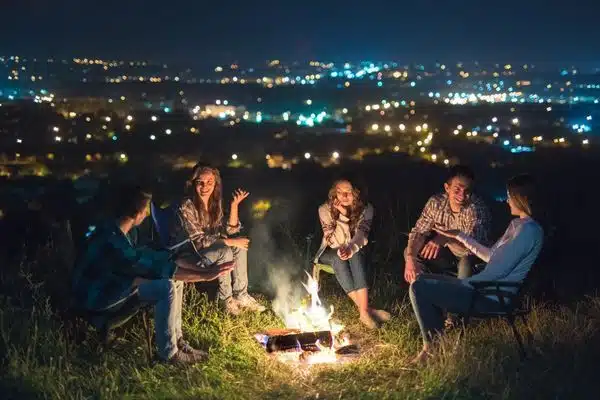 group in front of bonfire against a nighttime city skyline